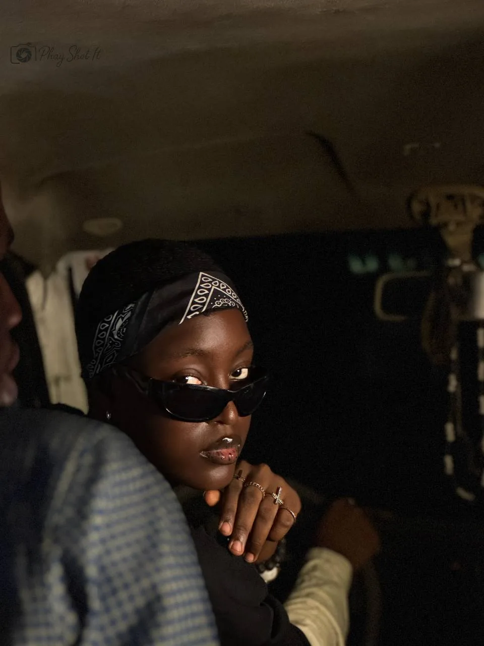 Woman in bandana and dark sunglasses, low-angle night portrait with dramatic lighting.